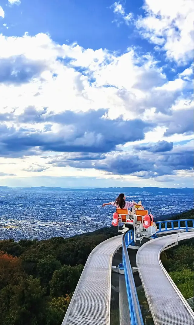 脚踏车沿弯曲高架轨道悬在山腰,下方是大阪平原