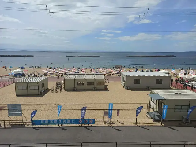 夏天的须磨海岸全景:海滩小屋、遮阳伞、「須磨海岸を笑顔に」横幅